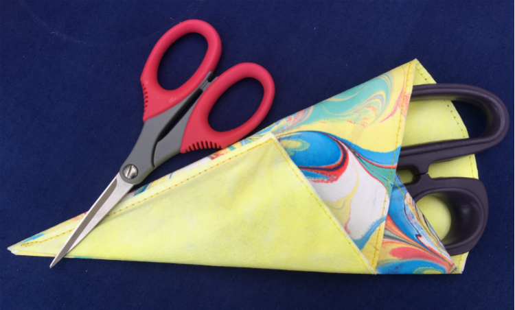 Completed scissor sleeve, containing large purple scissors with small red pair lying across the top.